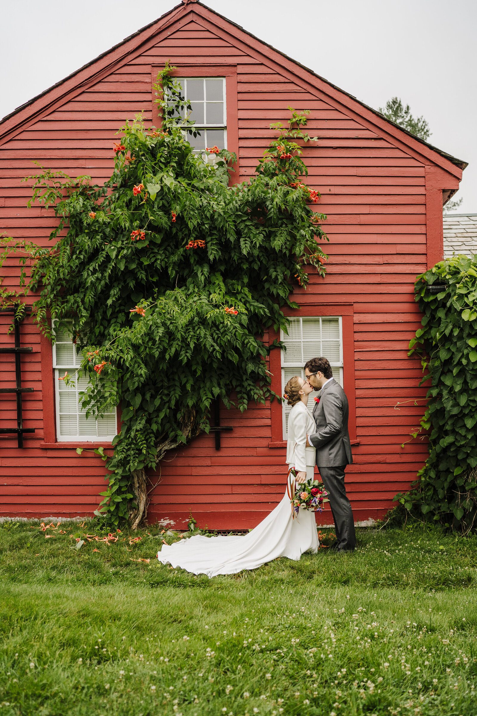 wedded couple stands in front of red building