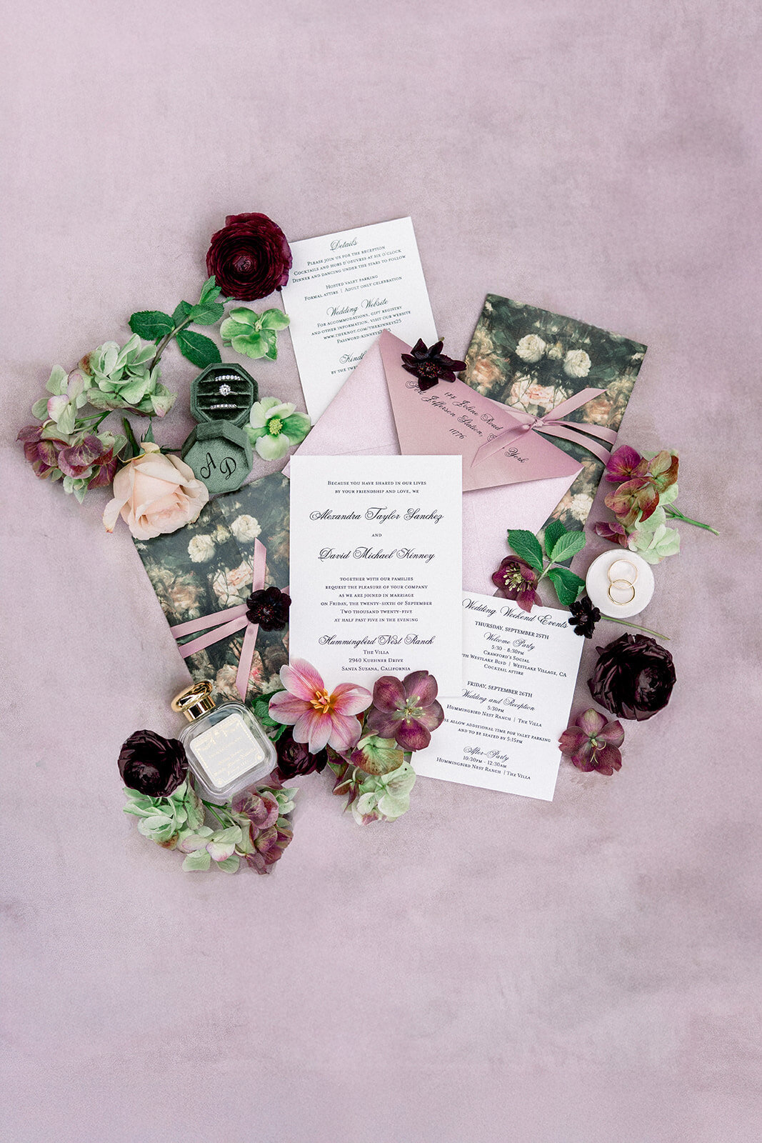 Wedding invitation suite styled with deep-hued florals on blush backdrop, captured in editorial detail photography.