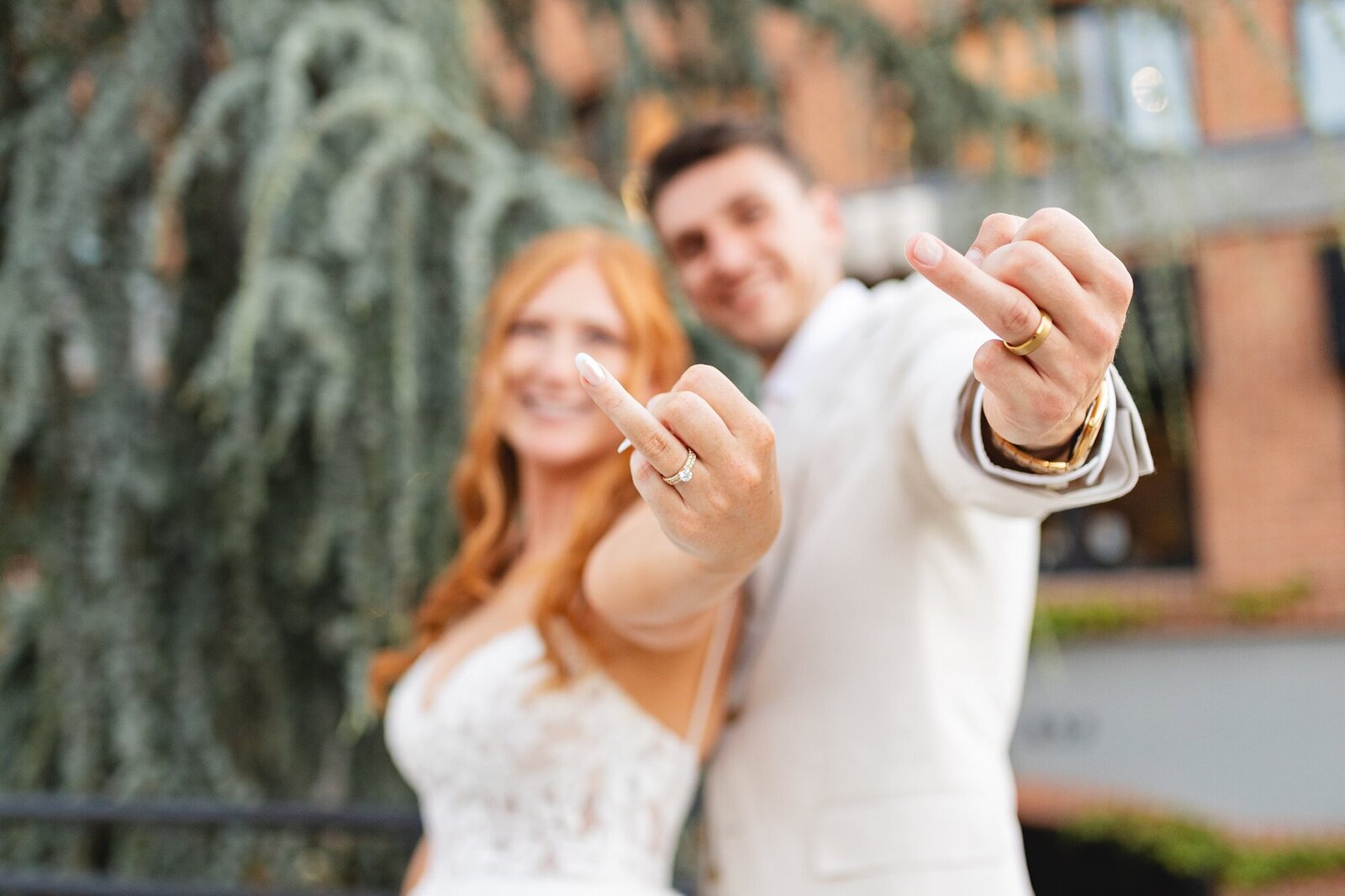 groom and bride showing off their wedding rings