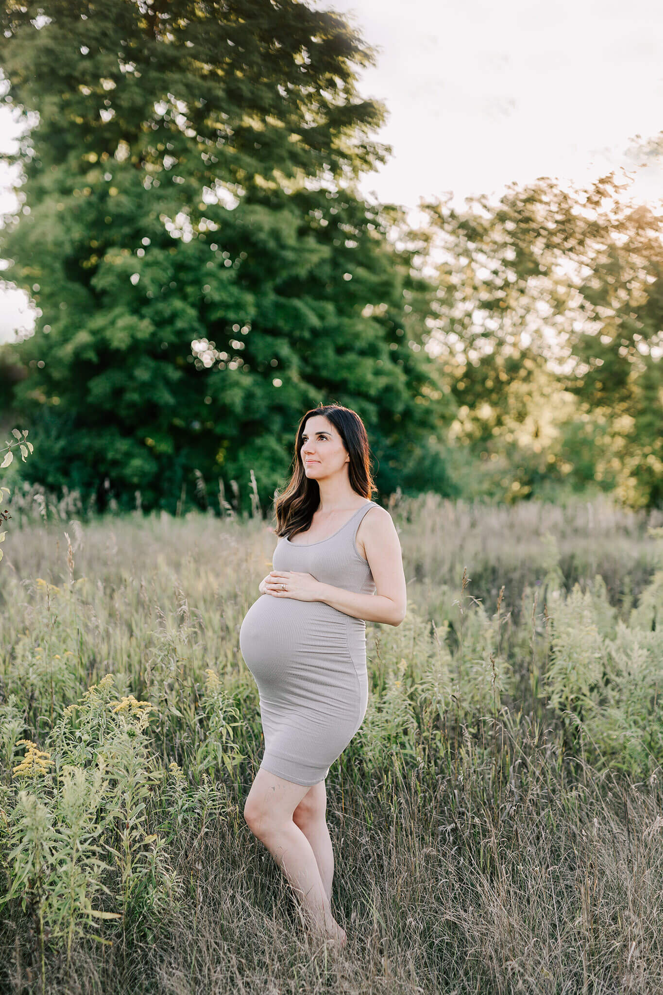 Expecting mother is photographed in a beautiful grassy field in September.