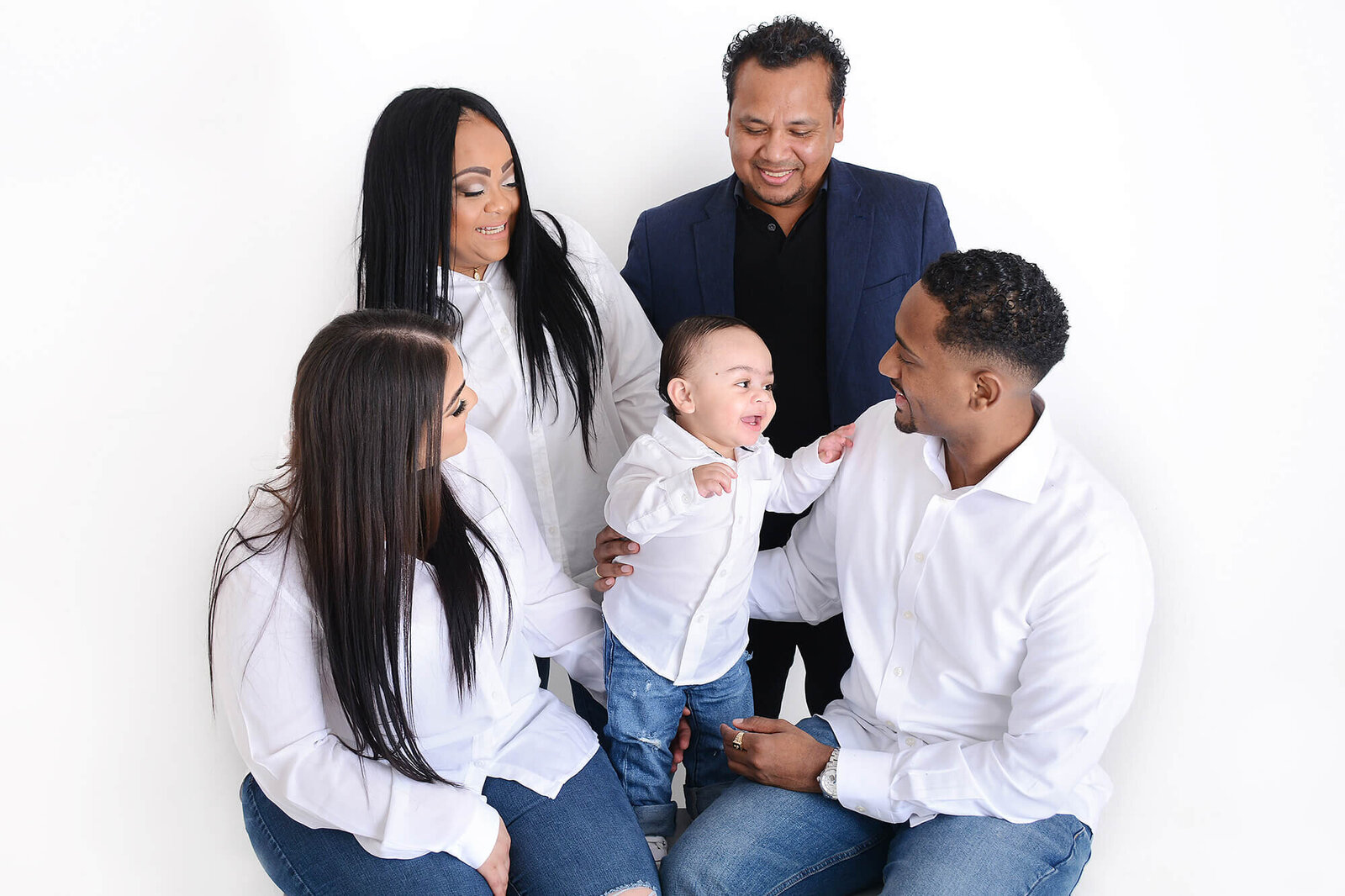 extended family smile at a baby boy at their photoshoot