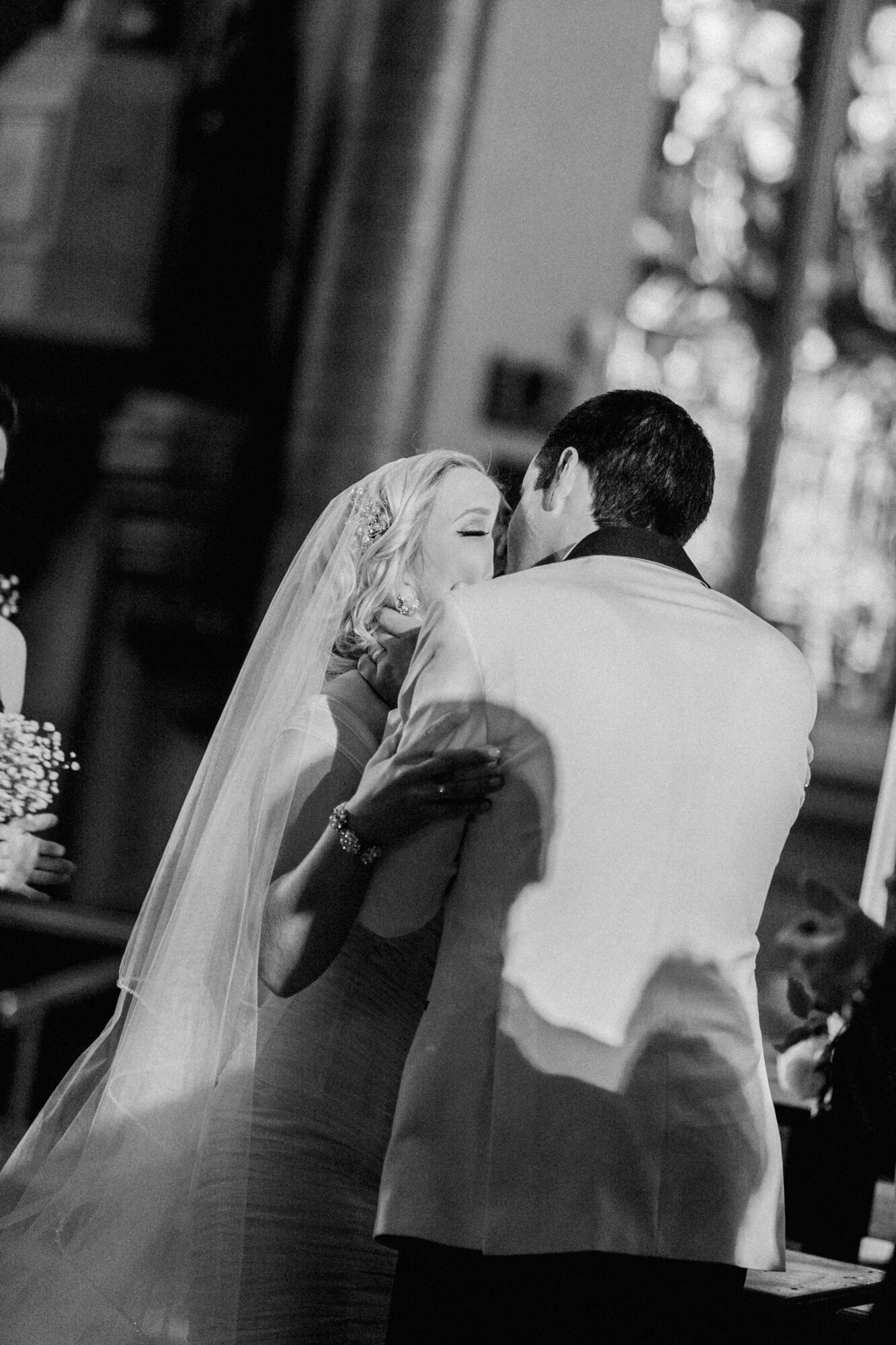A beautiful black and white photograph of a couple sharing their first kiss during their wedding ceremony