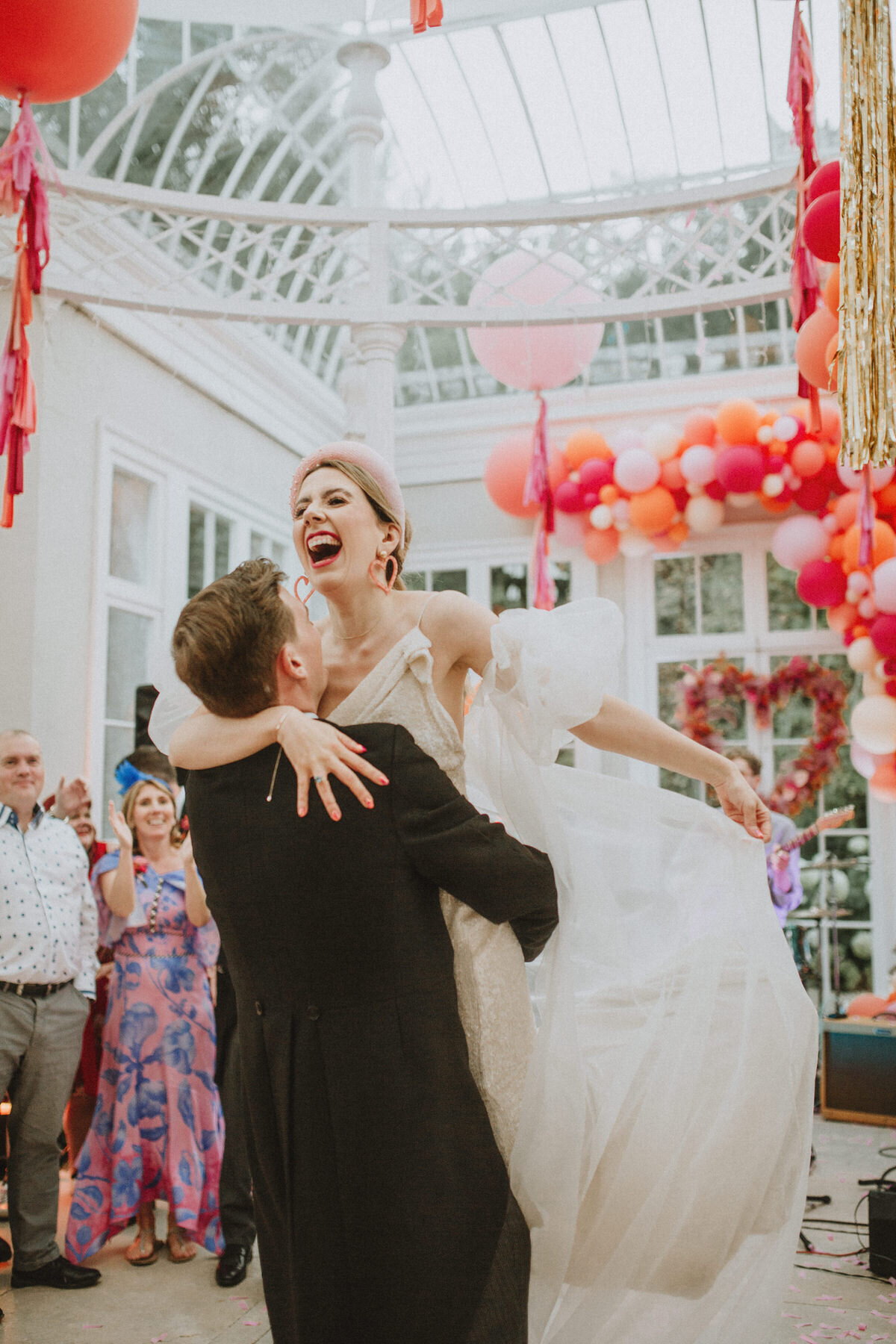 groom lifting bride at wedding celebration in domed conservatory