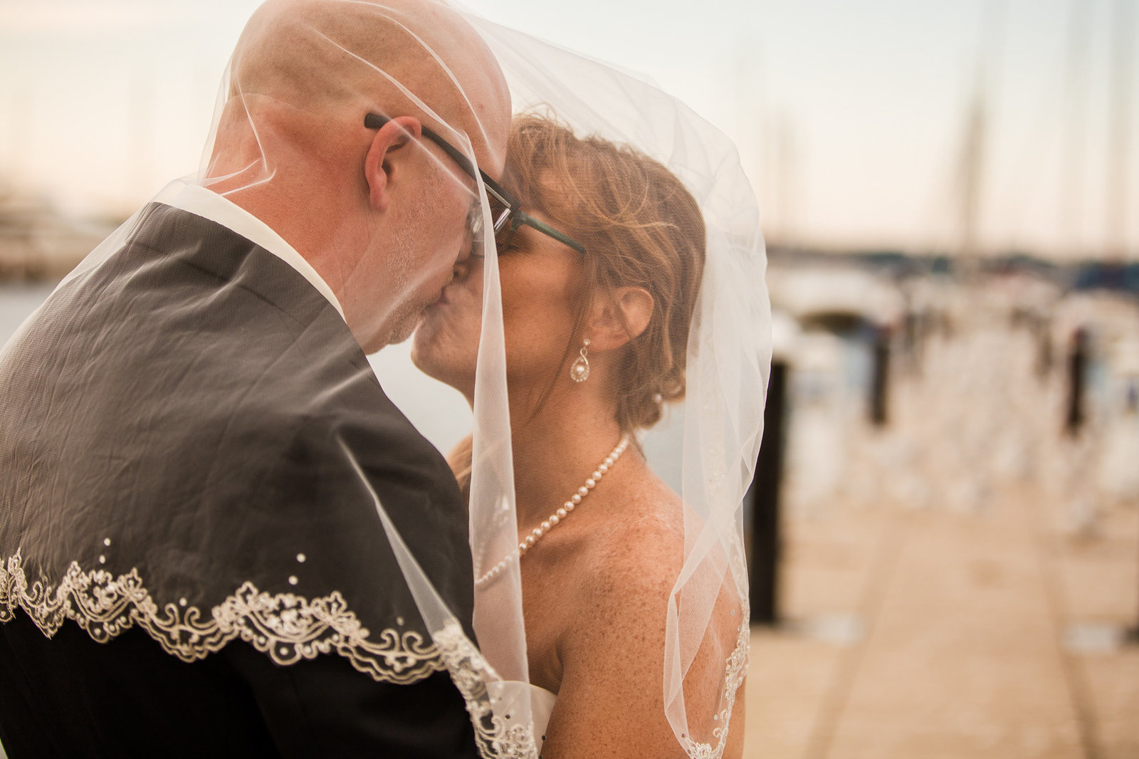 Bride and groom kiss under bride's veil on the dock at the Erie Yacht Club