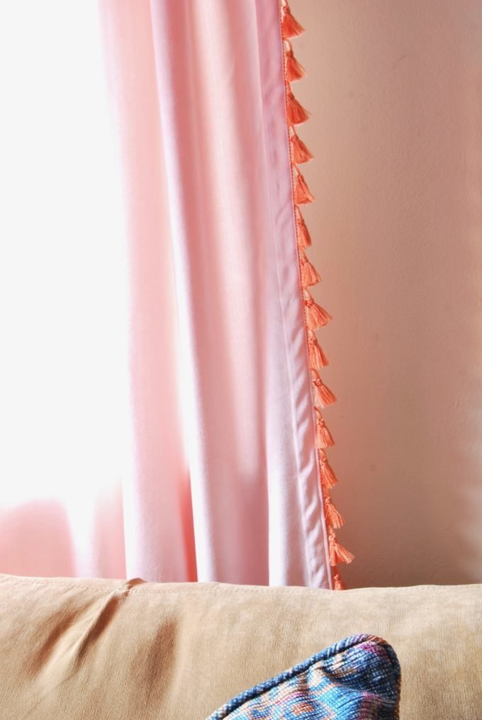 Pink sheer drapes with orang tassels.