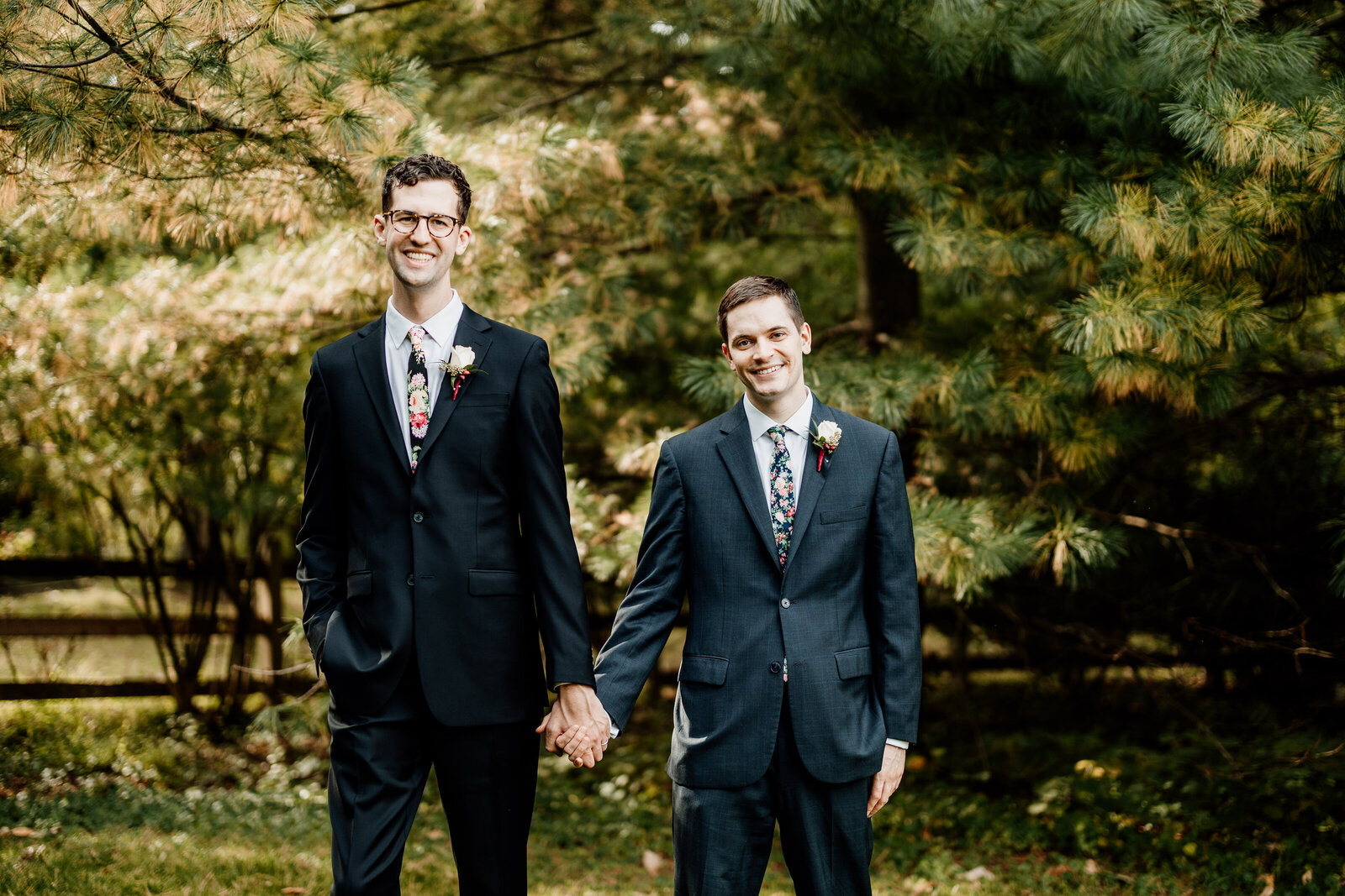 gay grooms holding hands in nature garden