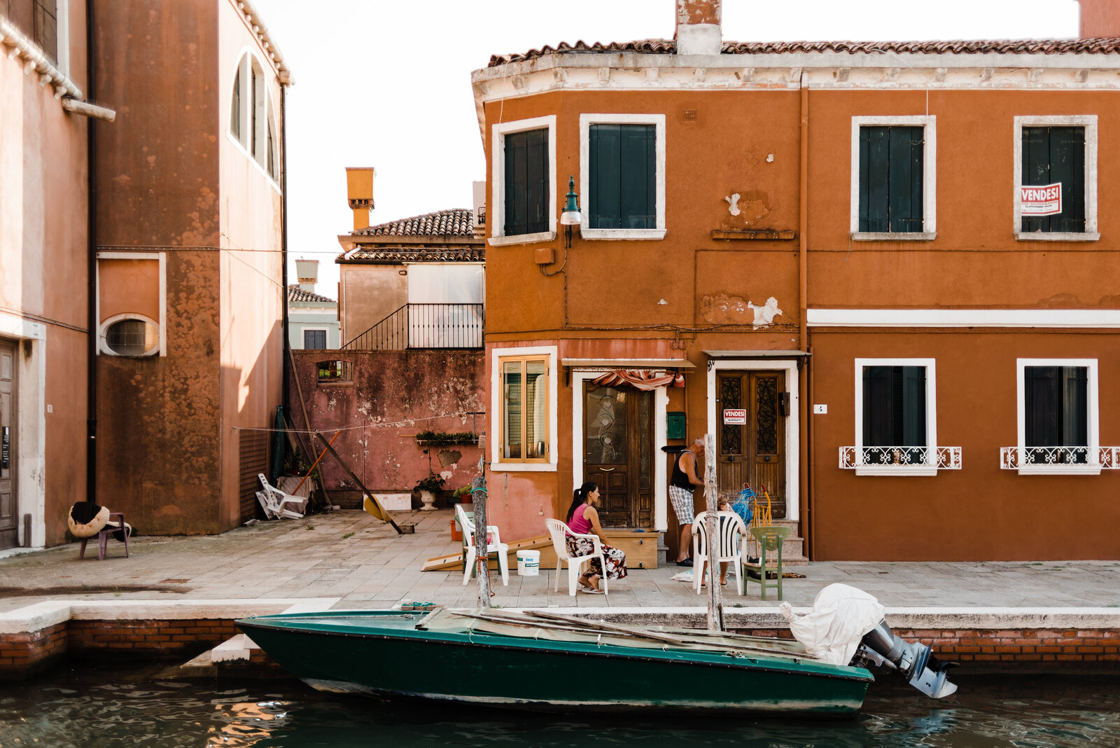 Family sitting outside of house in Burano, Italy