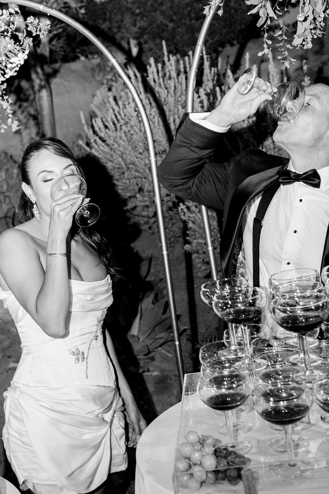 Black and white image of bride giving a toast with champagne, highlighting documentary-style wedding photography in Los Angeles.