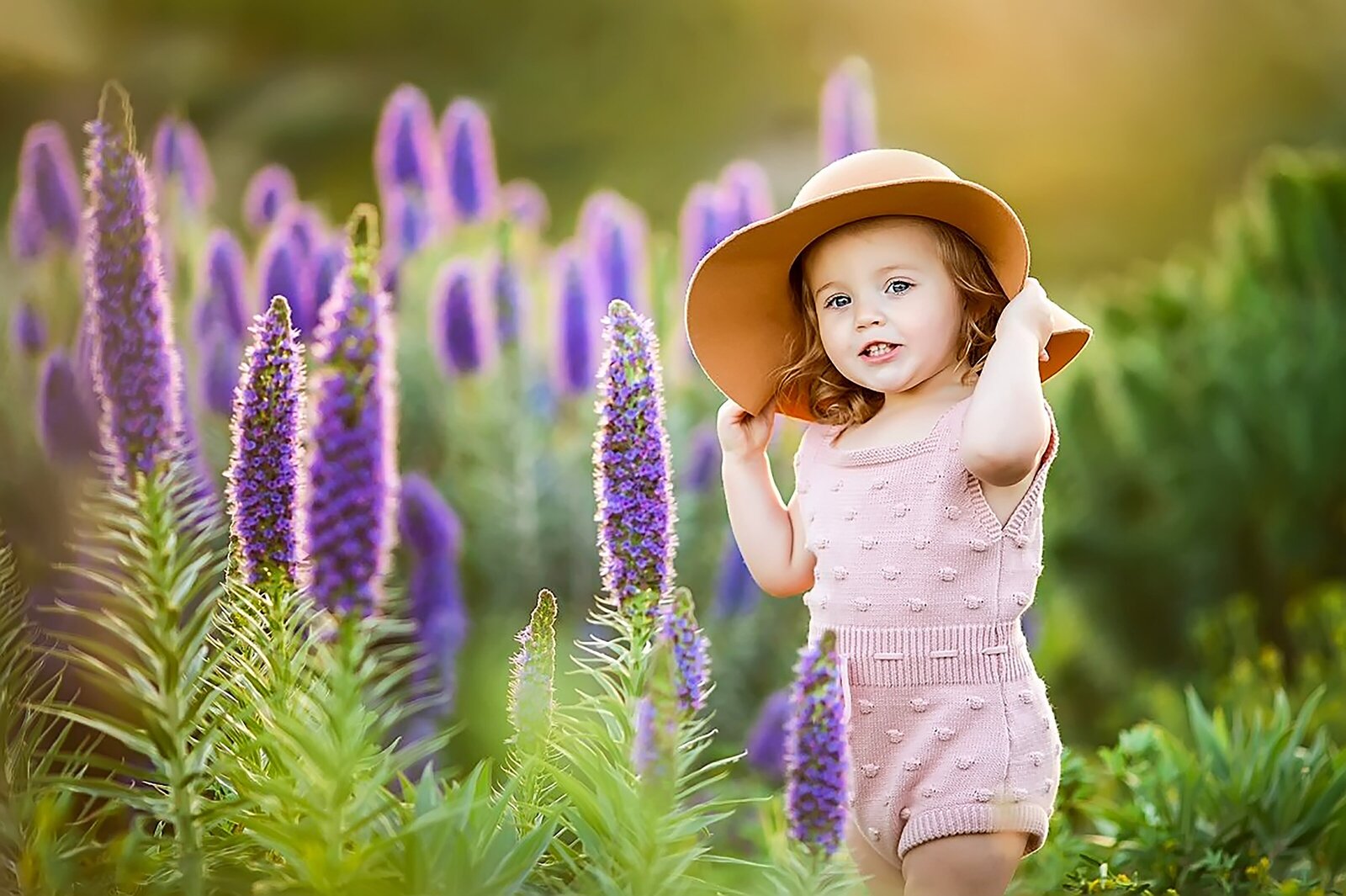 Toddler girl wearing sun hat posing among wild flowers in Del Sur North San Diego County