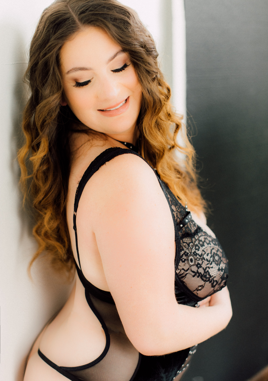Woman with long brown hair hugging herself during her boudoir photoshoot long island NY