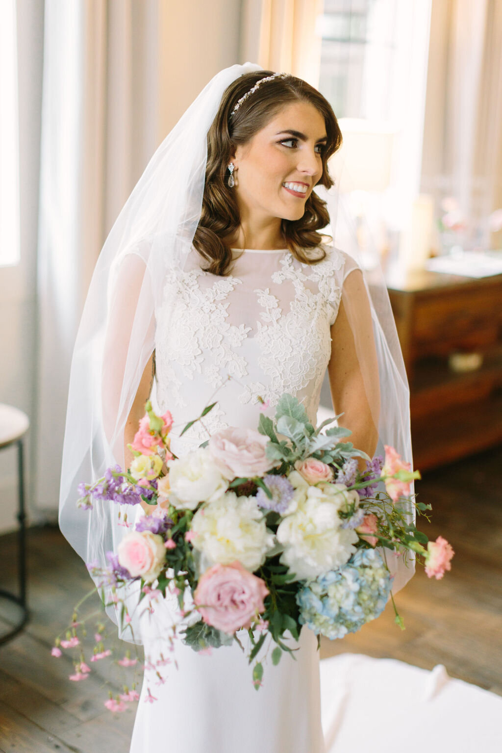 Bride in white gown with pink and purple flower bouquet
