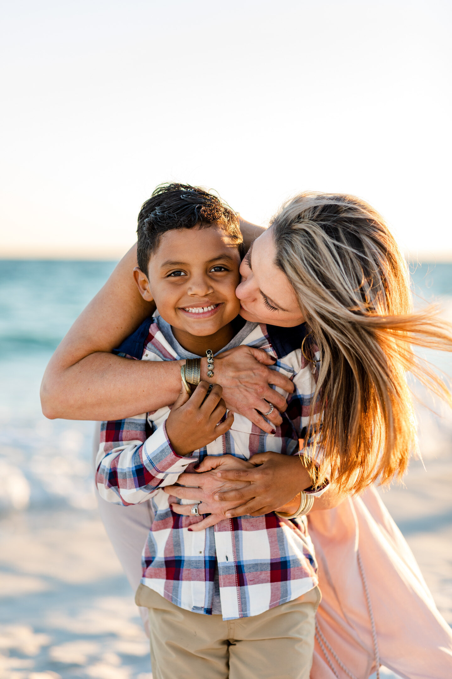 Mother kissing son on the cheek during family photography session on Pensacola Beach.