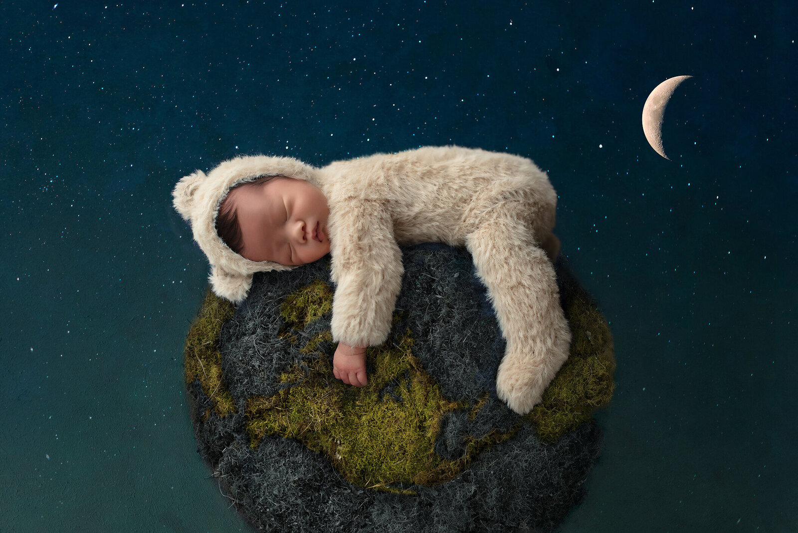 Newborn boy dressed as teddy bear hugs the world