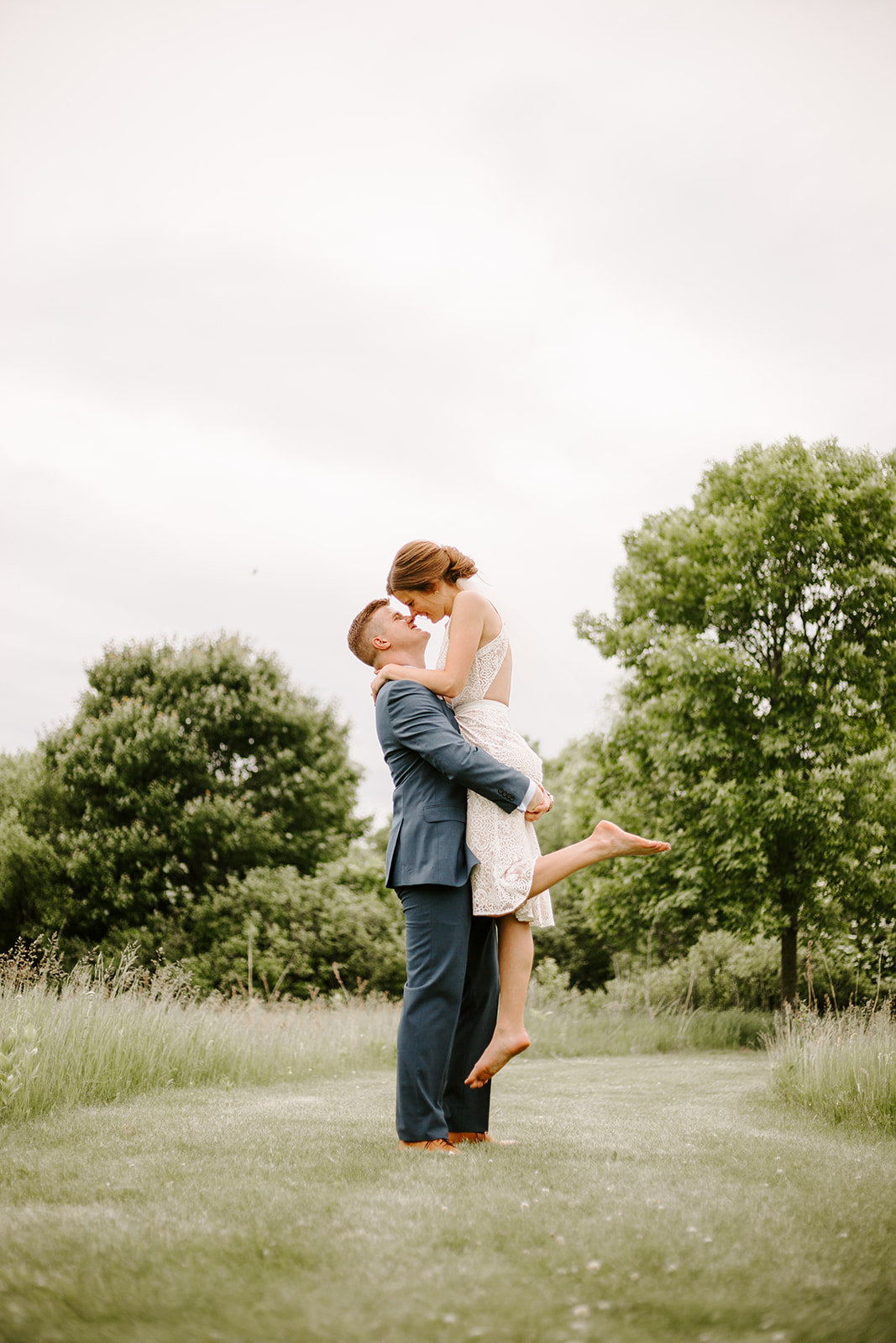 Groom lifting up his bride in a field during their Minneapolis Elopement