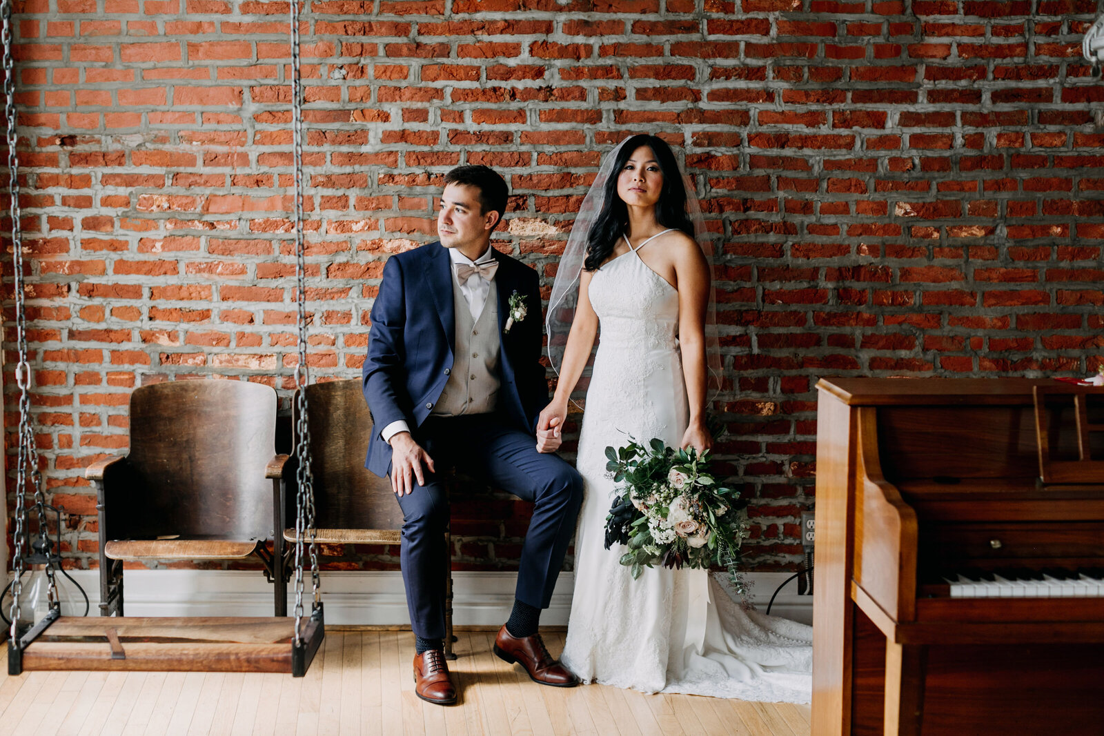 bride and groom with brick wall and piano