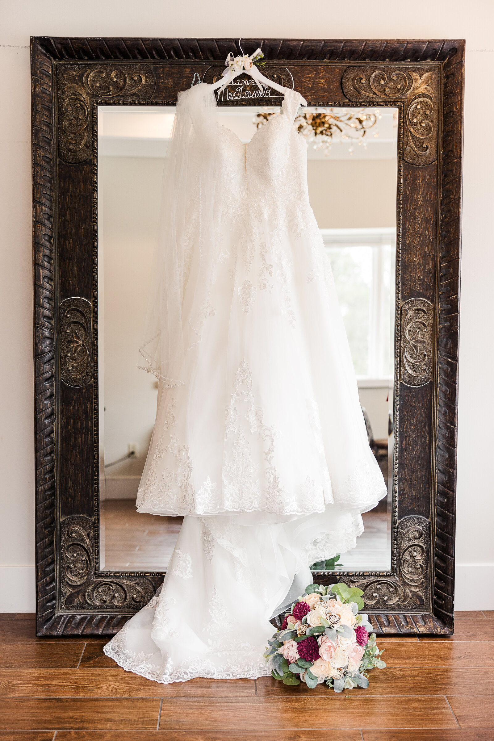 Wedding dress against large mirror with bridal bouquet