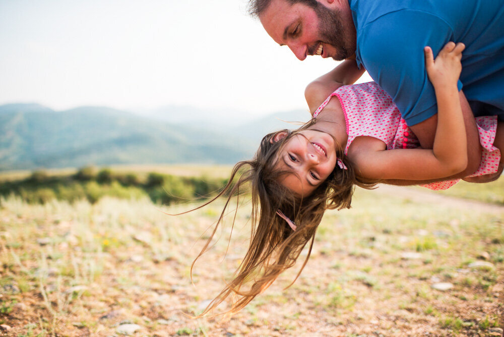 a dad tickles her daughter on a mountain top in colorado