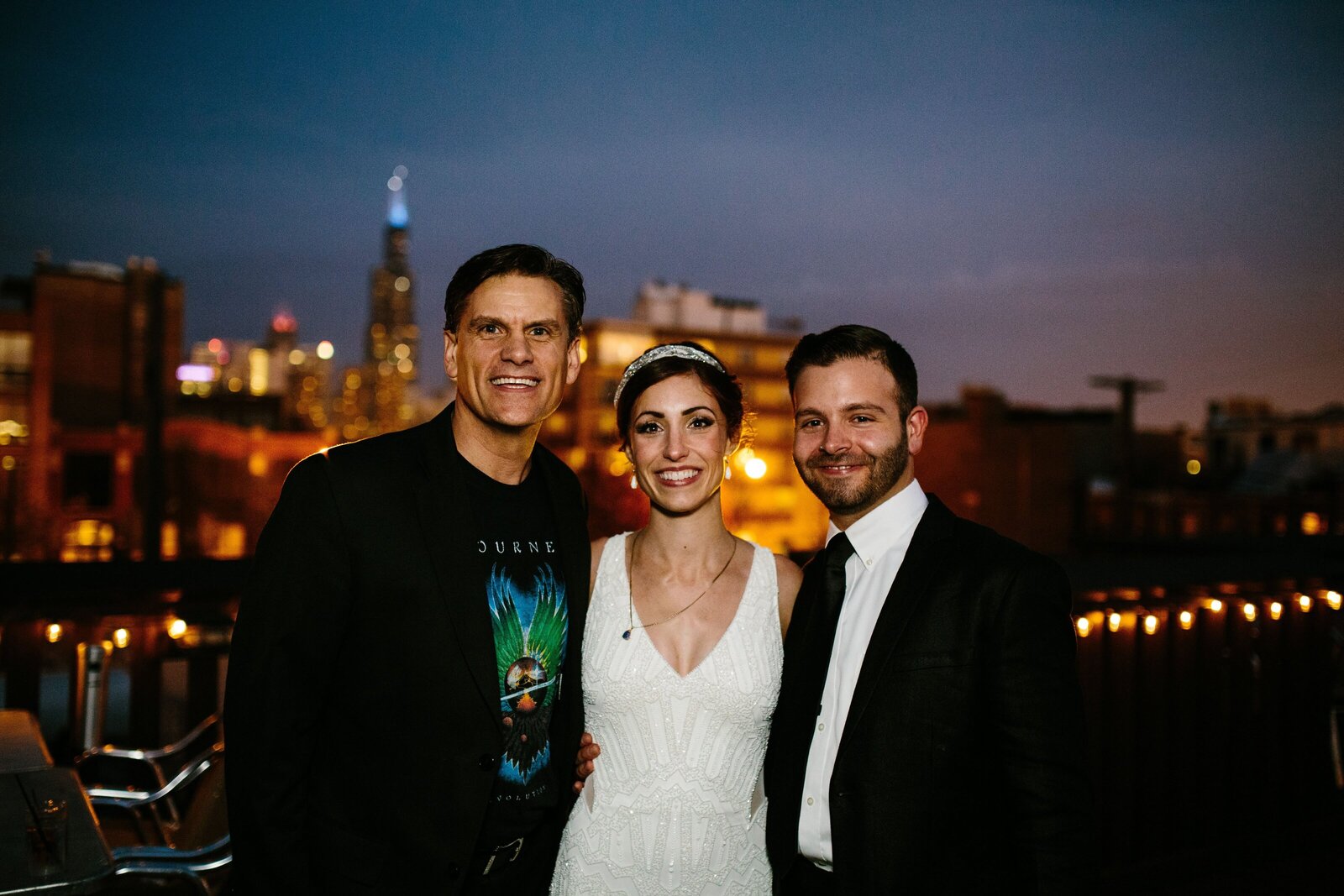 Bride and groom smile with wedding officiant after their wedding ceremony with Chicago skyline in the background