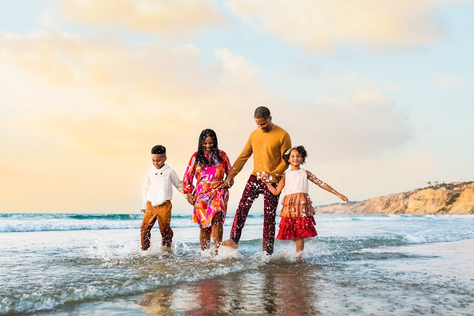 Parents with two children splashing in the waves on the beach at Scripps Pier