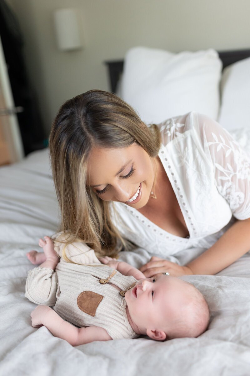 Mom looking at newborn baby laughing, taken by nj newborn photographer