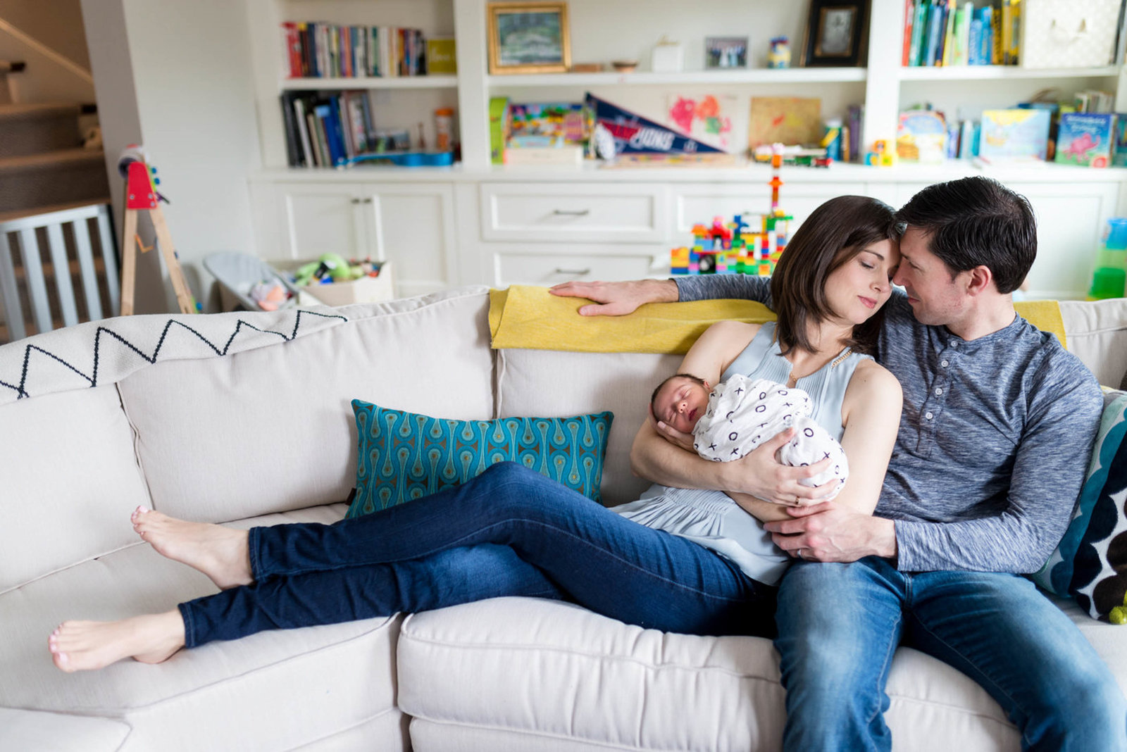 Couple hugging on couch with newborn in home