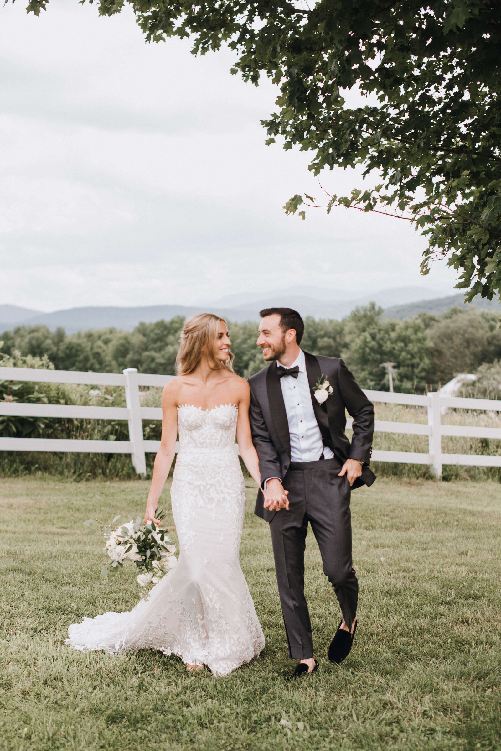 A bride and groom in a tuxedo  walking hand-in-hand on a farm in the Catskills mountains