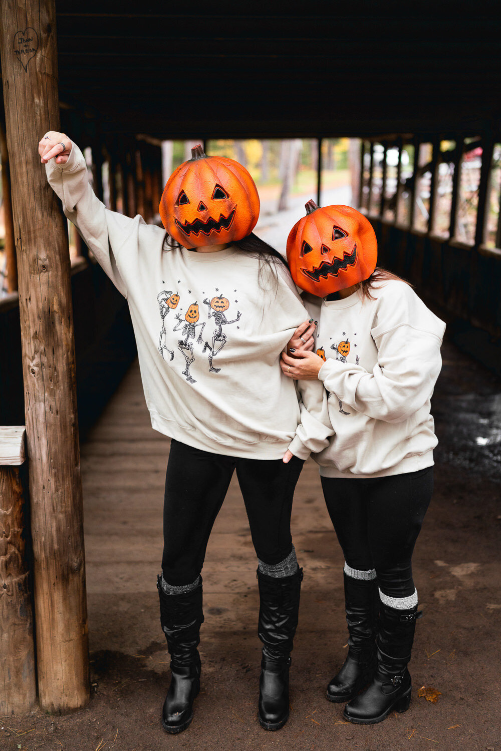 Women in pumpkin Halloween masks snuggle on bridge in Minnesota.