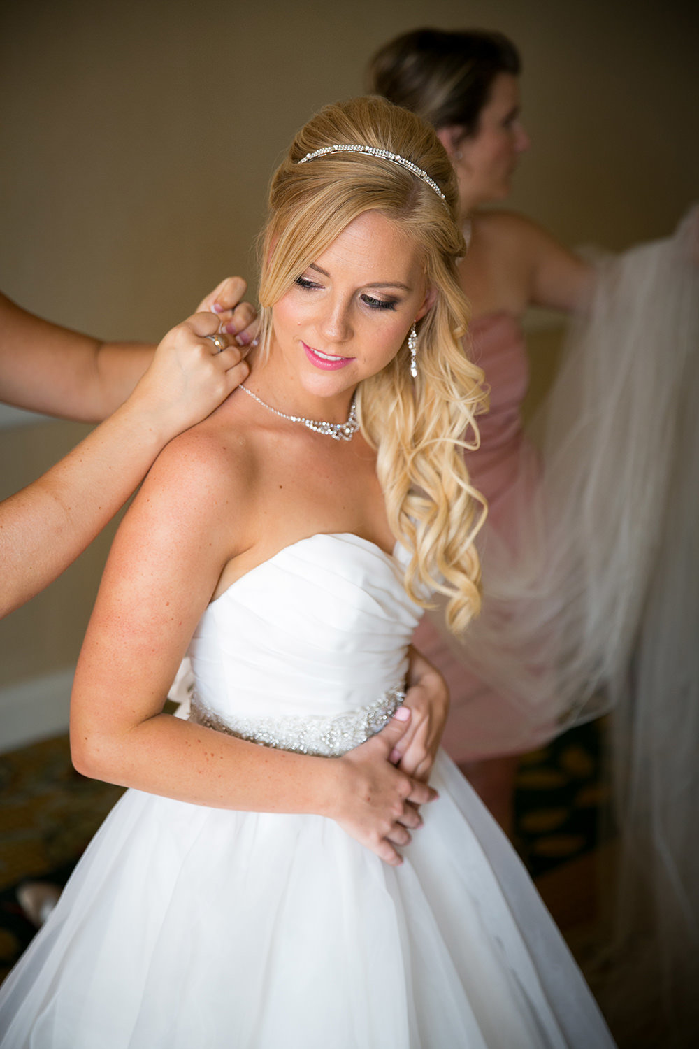 Beautiful blonde bride putting on the finishing touches for her wedding day