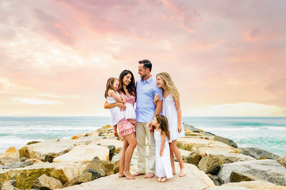 sunset photo of family on rock jetty in San Diego