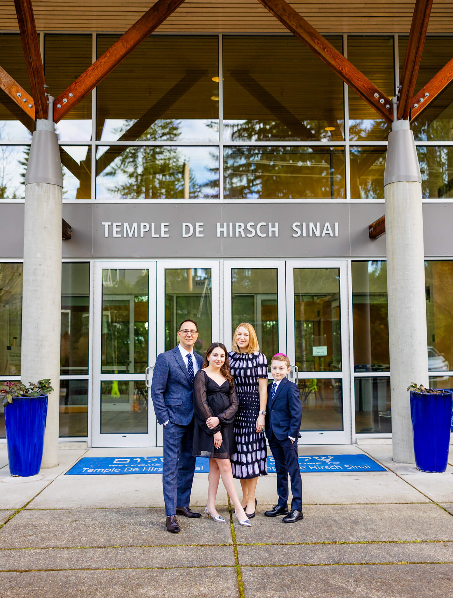A mom and dad stand outside the Temple entrance with their teen daughter and young son