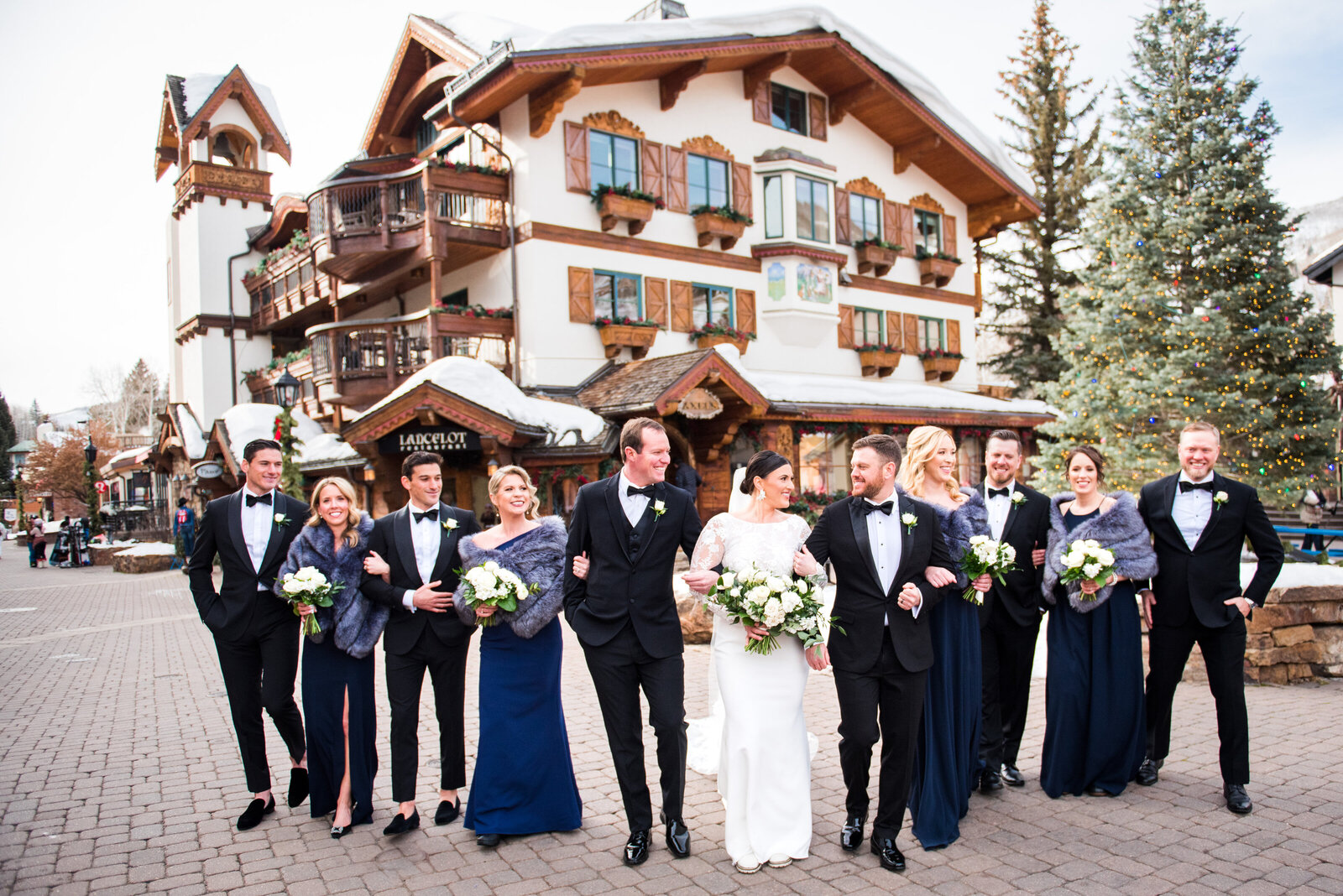 A bride and groom walk toward the camera with their wedding party in Vail, Colorado.