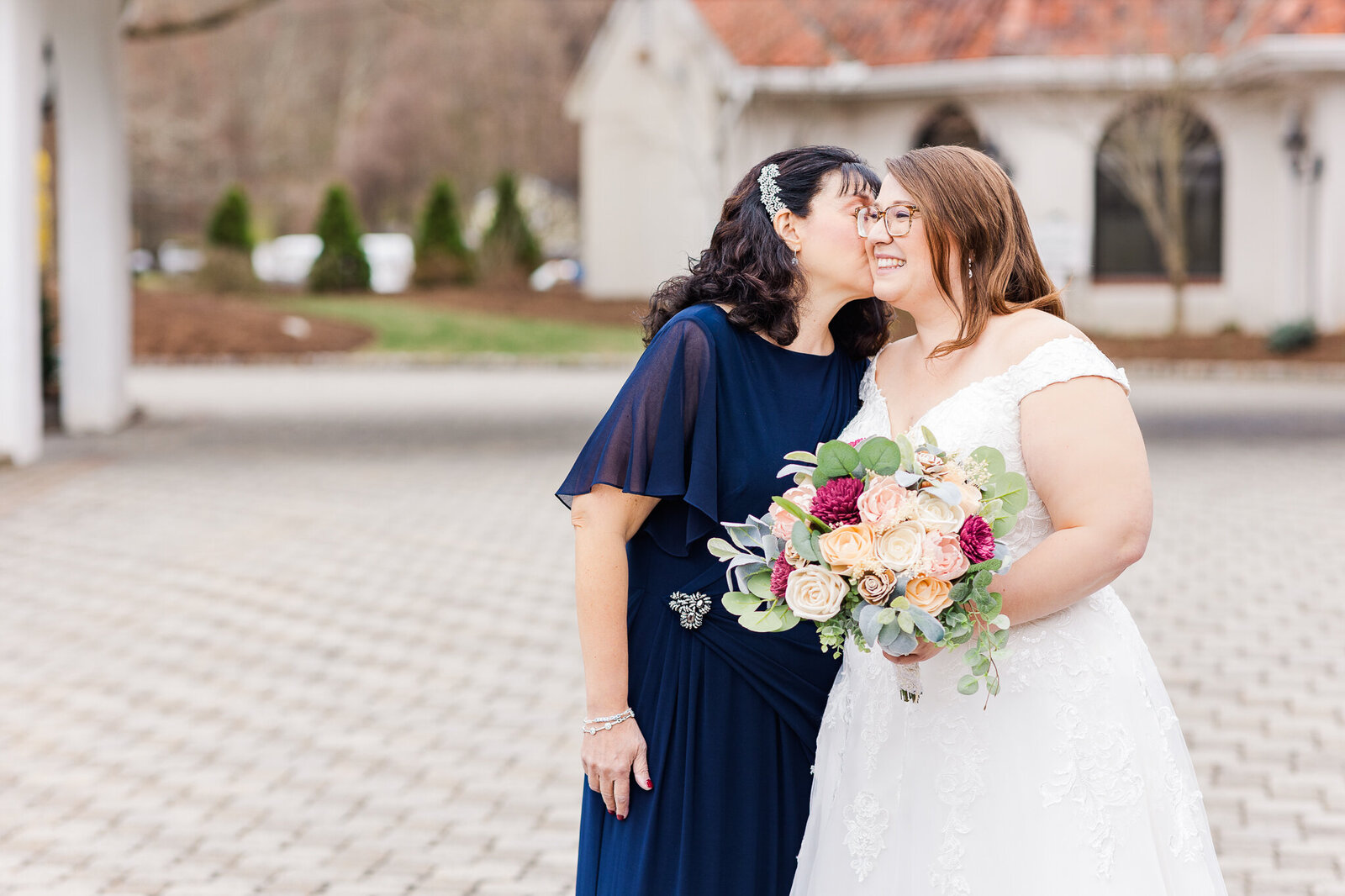 Mom kissing bride on cheek on wedding day