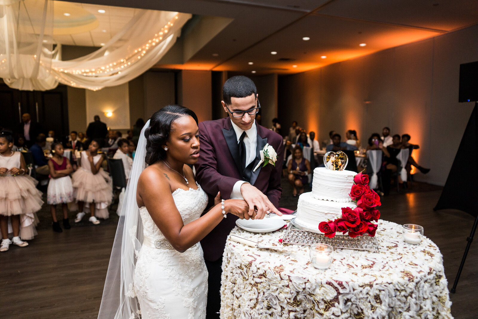 Newly wedded couple cutting their two-tiered white cake