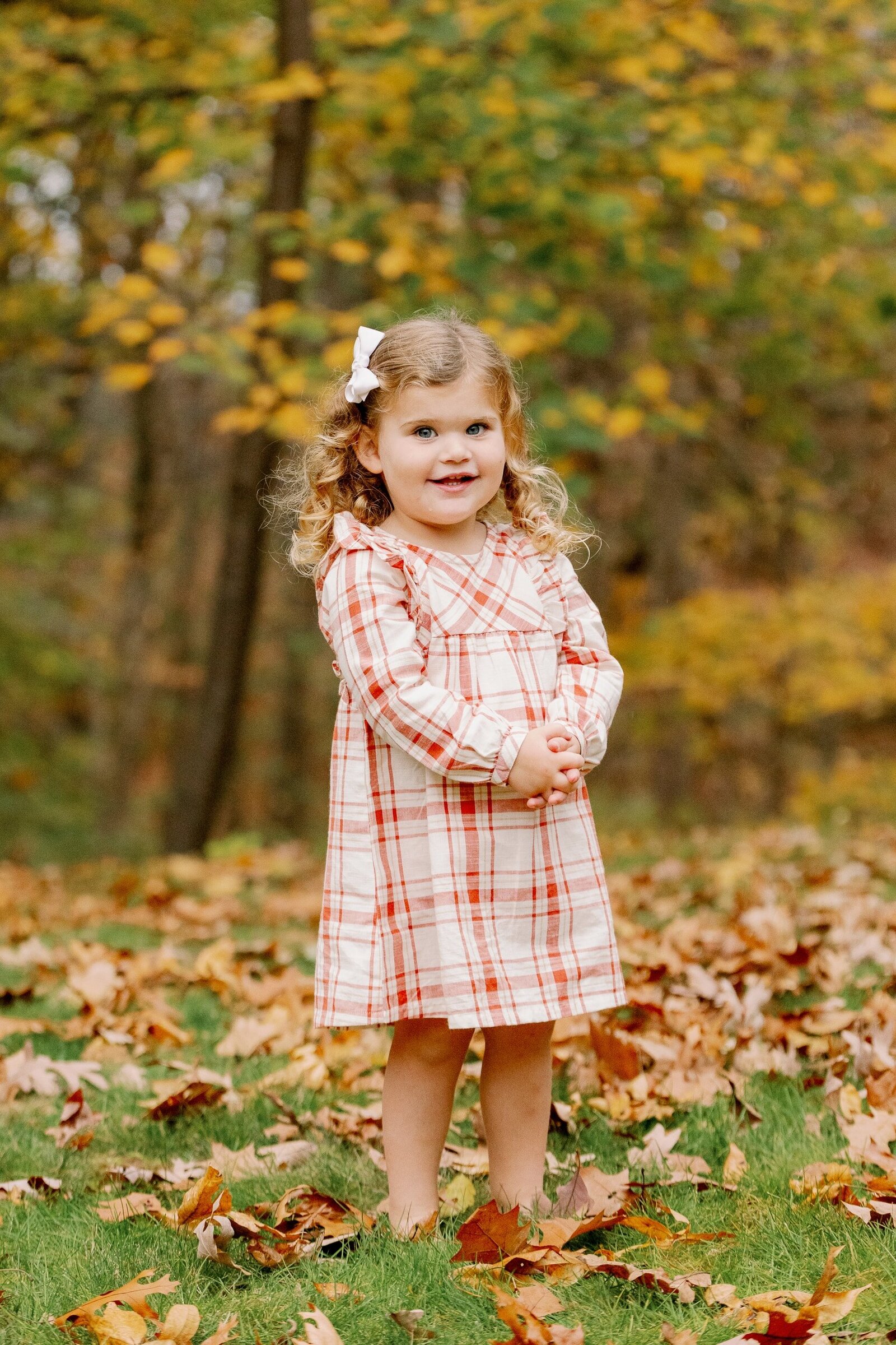 young girl in dress among fall leaves
