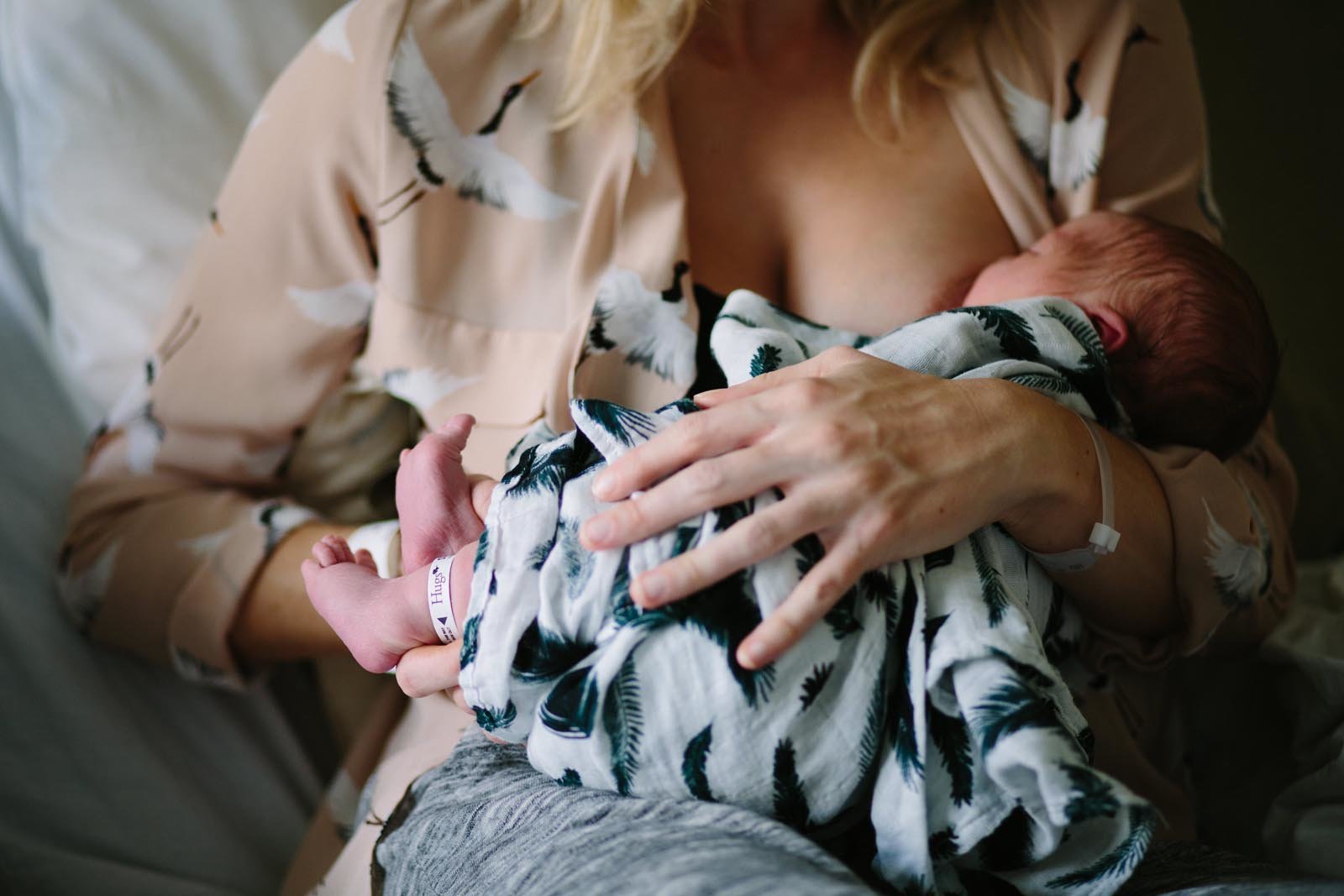 closeup of mom in crane shirt breastfeeding her newborn daughter at the hospital