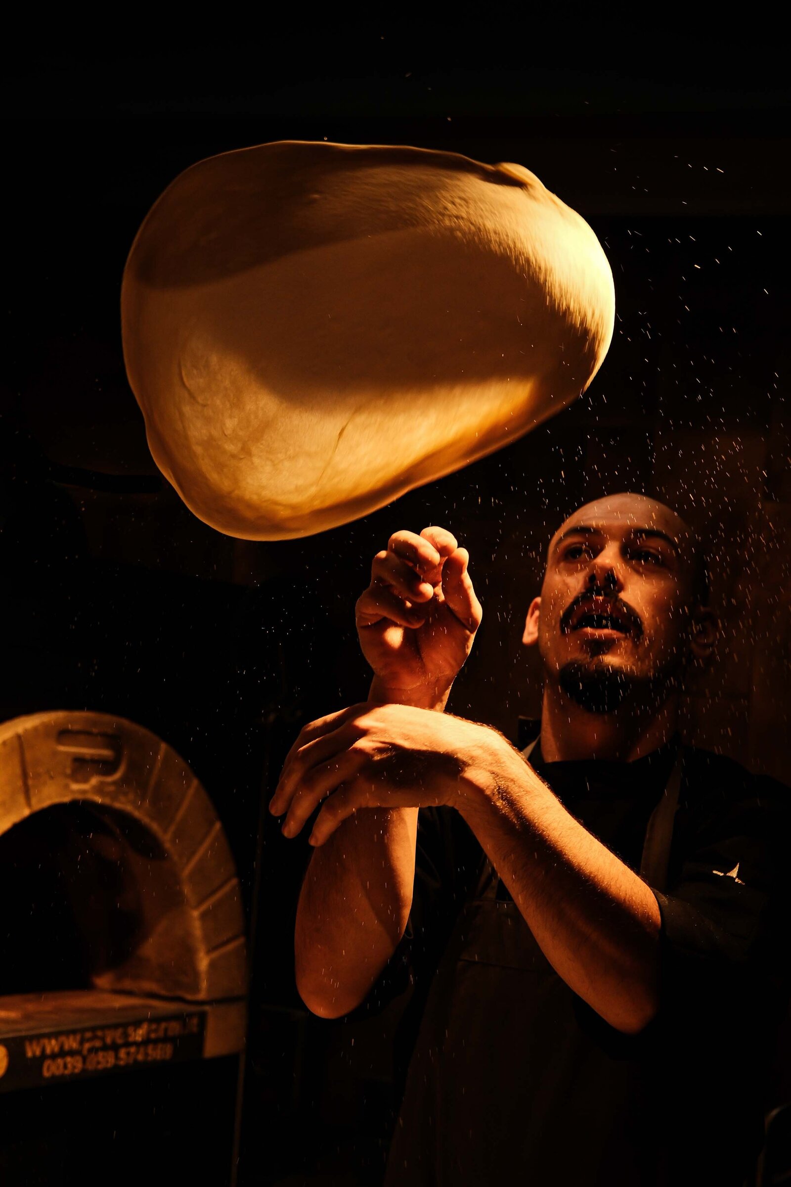 Chefkok die pizza deeg in de lucht gooit, cinematisch beeld