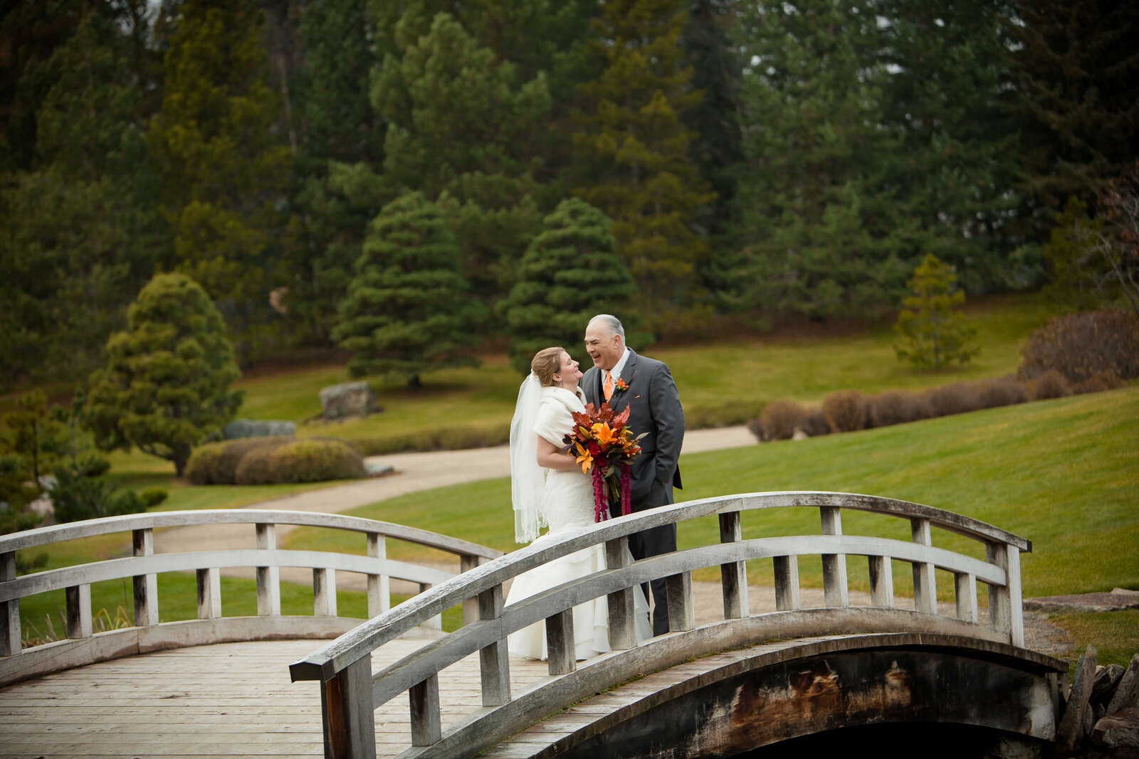 Bride and Groom laughing  on a bridge at Japanese Gardens Alberta