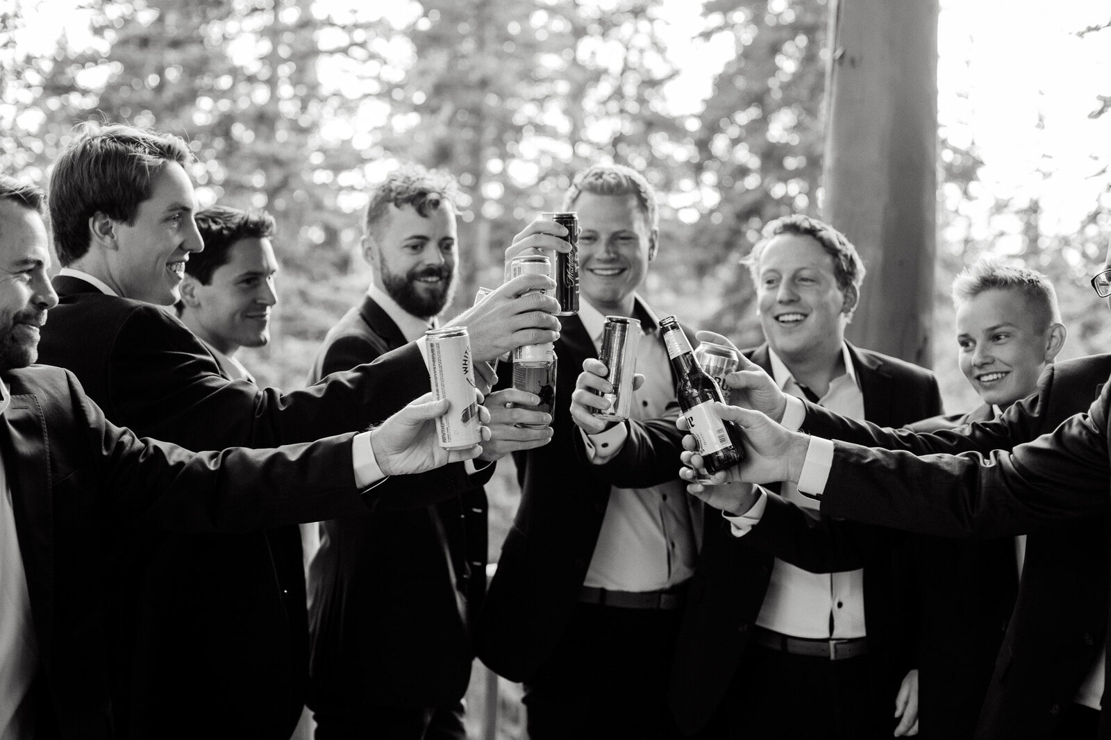 Black and white photo of groomsmen having fun and making a toast at wedding in Colorado.