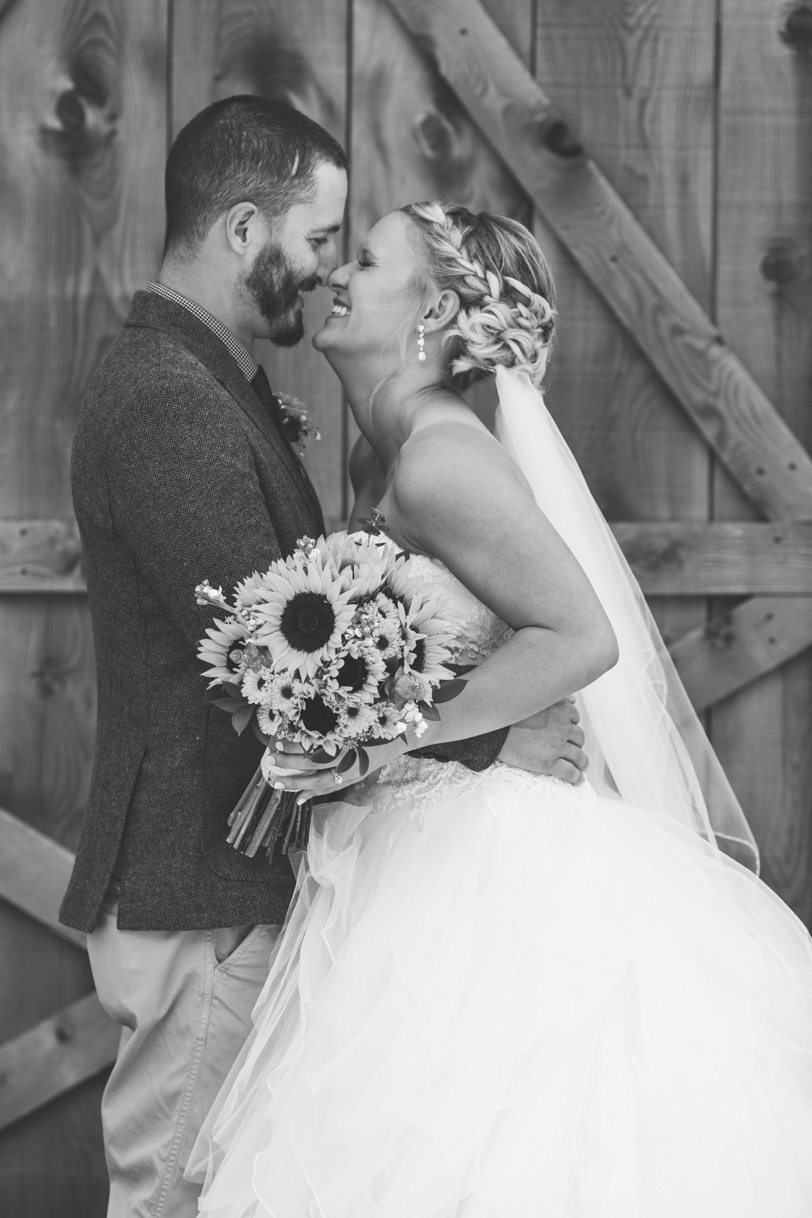 bride and groom  give an eskimo kiss in front of a barn in erie