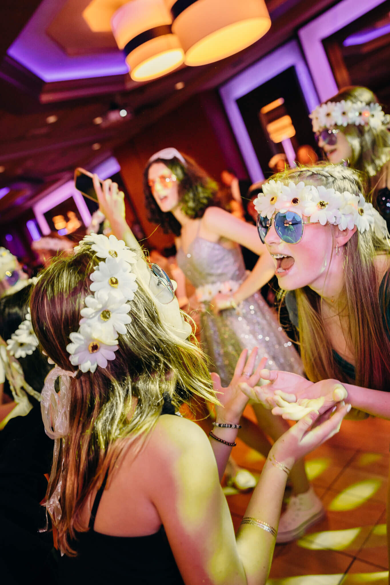 Teenage girls dance and play in blue glasses and flower headbands on the dance floor