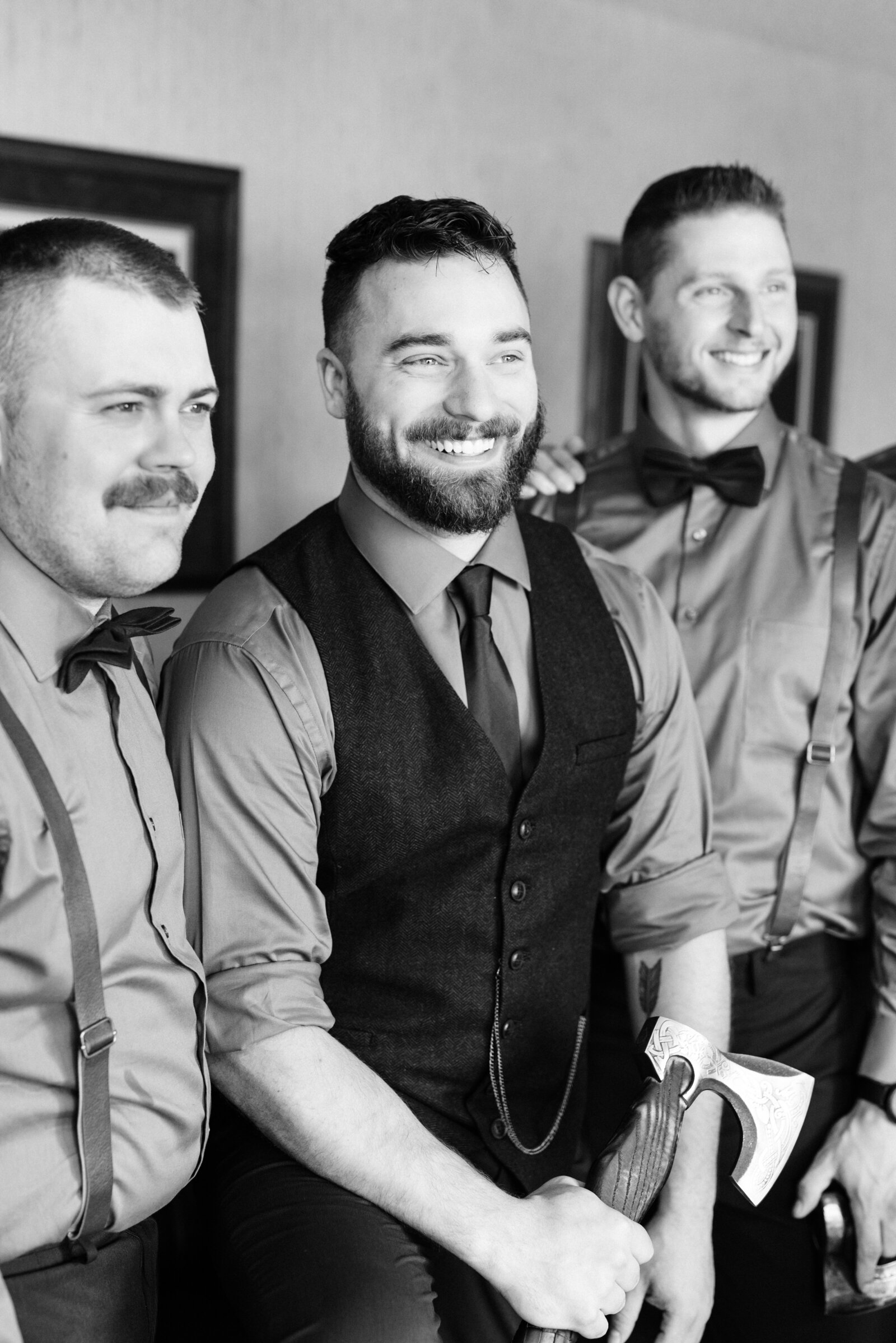Groom smiling with groomsmen holding ax
