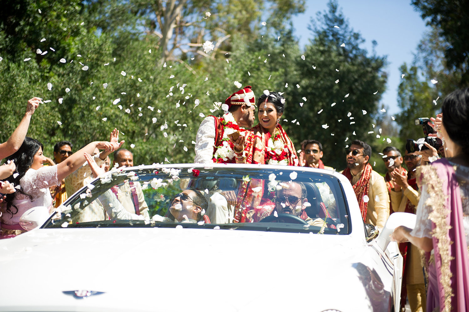 Bride and groom are showered with flower petals and rice after their Hindu wedding ceremony
