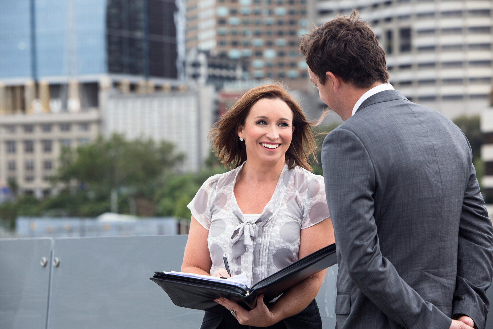 Female Lawyer talking to client with city buildings in the background