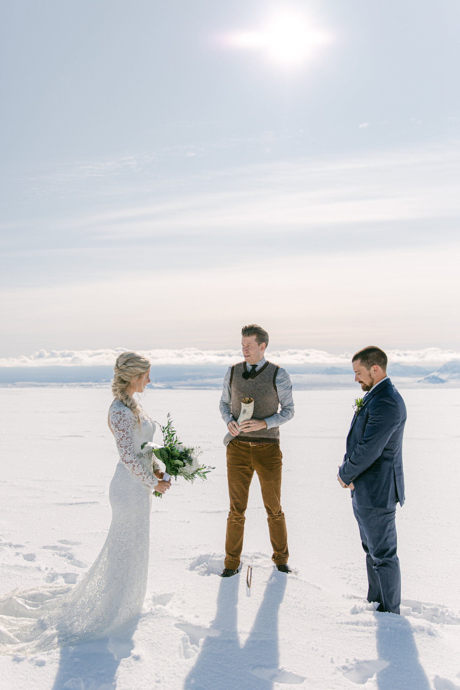 bride and groom and wedding officiant on top of a glacier in iceland exchanging vows