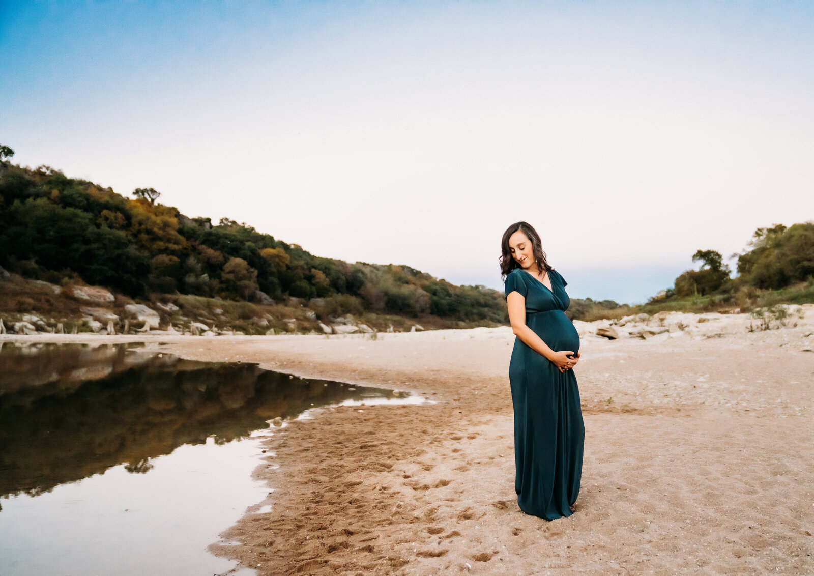 Maternity Photographer, an expectant mother stands in the sand near a small pond