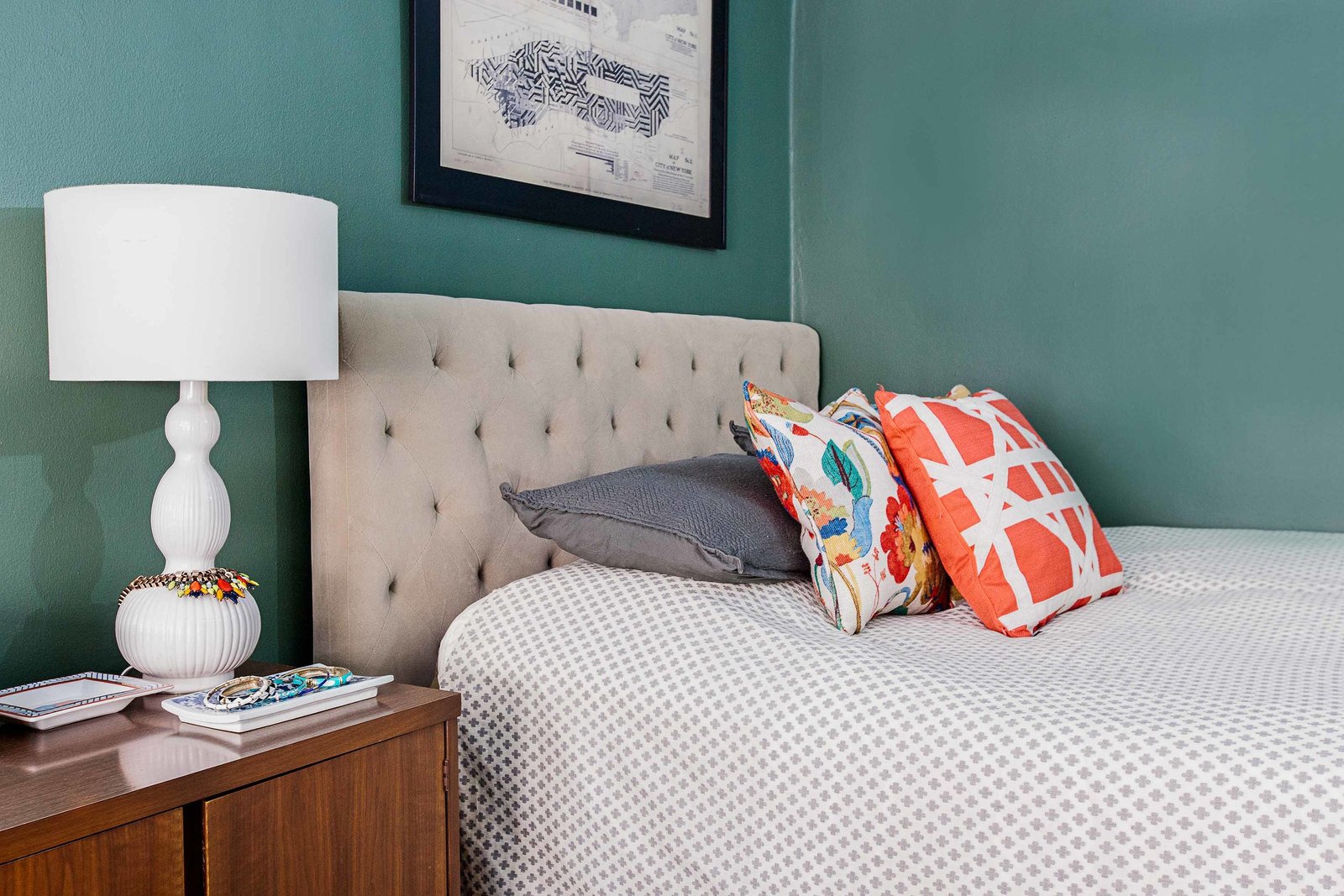 A bed with a tufted headboard and sideboard end table.