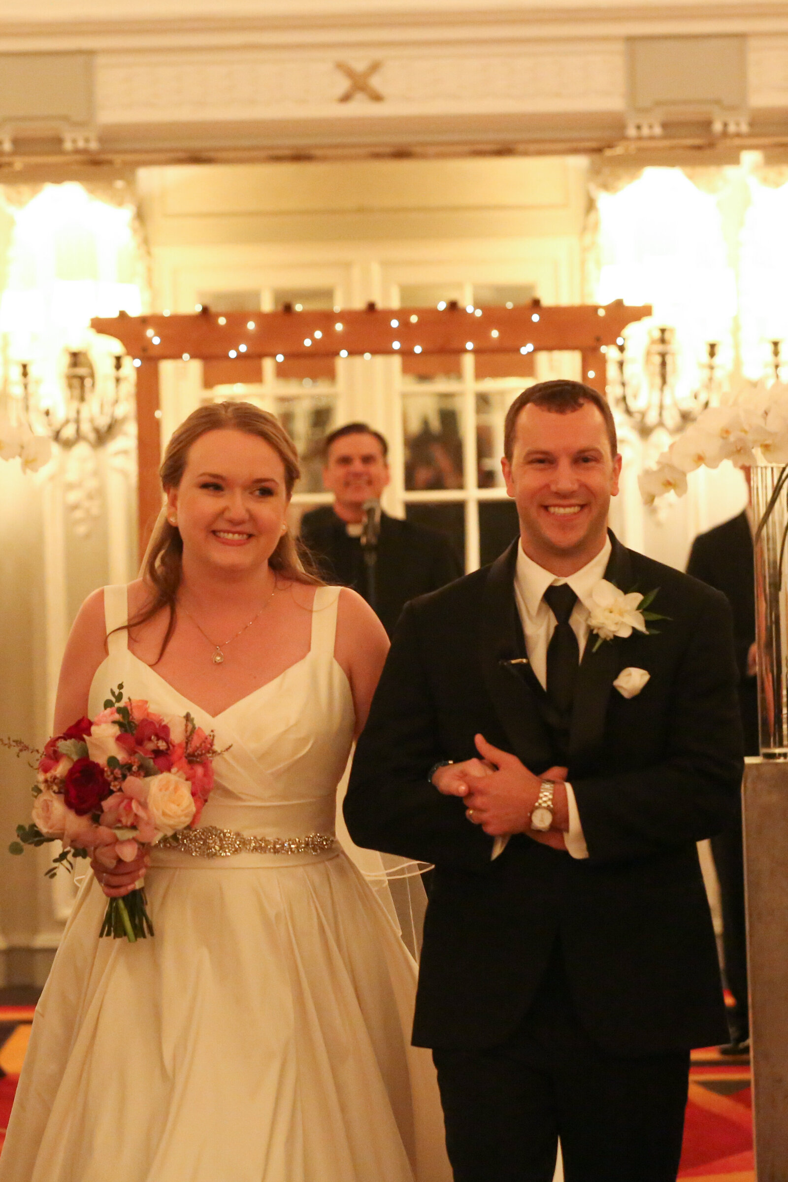 Bride and groom smile as they walk back down the aisle as a married couple arm in arm