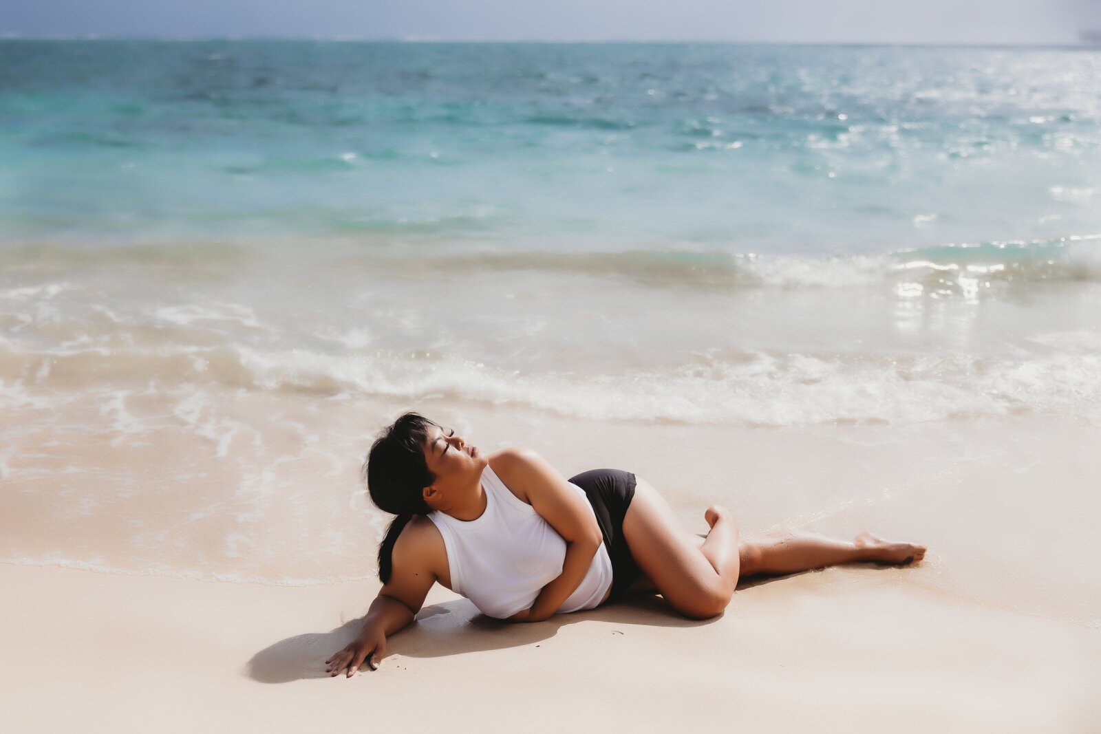 Boudoir photo of woman lying on Hawaii beach wearing white tee