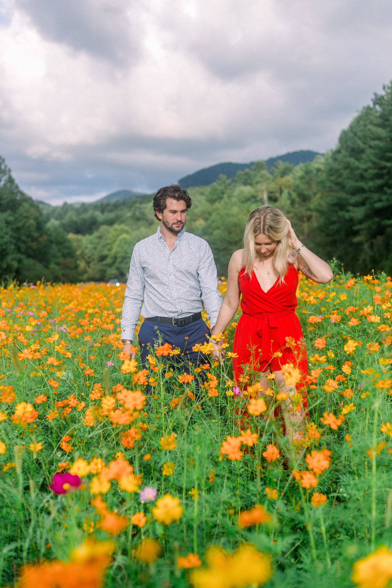 Couple walking through a field of wild flowers captured by Staci Addison Photography