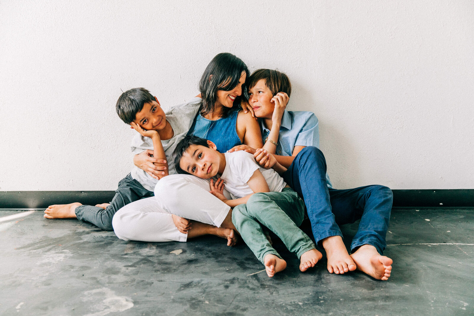 mom with three boys sitting on concrete floor and snuggled in close
